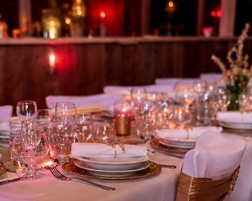 Table de fête dressée pour un dîner à thème : verres en cristal, assiettes dorées et lumière rouge