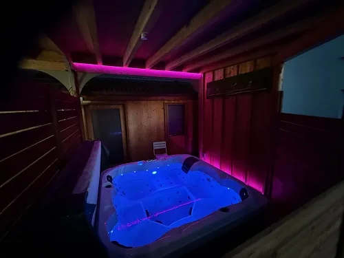 Le jacuzzi sous charpente, éclairé de bleu et de rose