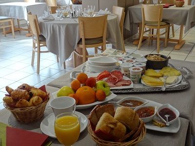 Petit-déjeuner servi en salle : viennoiseries, fruits, fromages et confitures