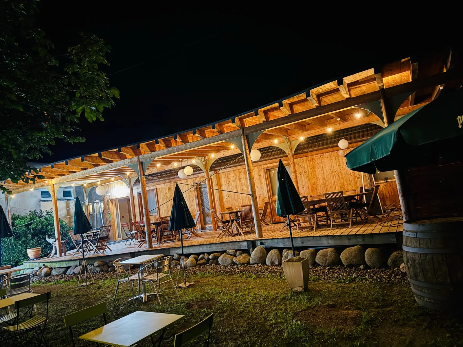 La terrasse couverte en bois, éclairée de guirlandes à la nuit tombée