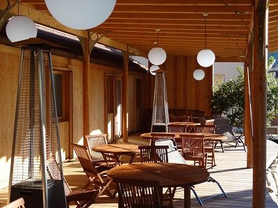 La terrasse en bois au soleil, tables en teck et lampes globes
